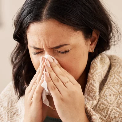 Frau schnäuzt sich die Nase.