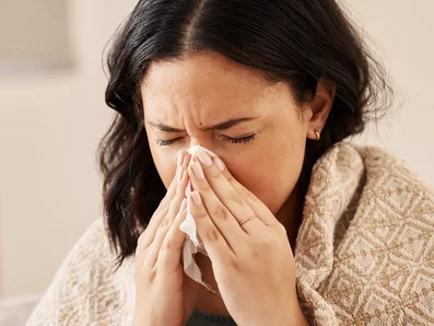 Frau schnäuzt sich die Nase.