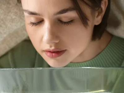 Junge Frau inhaliert heißen Wasserdampf.