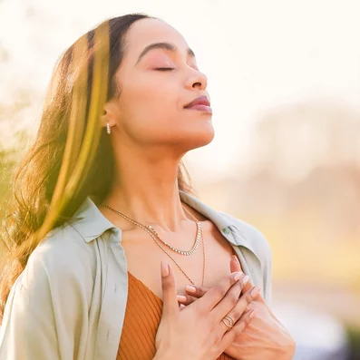 Frau nimmt genüsslichen Atemzug in der Natur.
