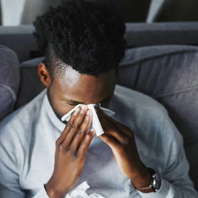 Frau und Mann mit Grippe oder Erkältung sitzen auf einer Couch.