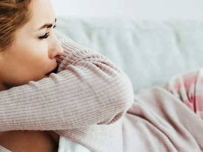 Frau auf der Couch hustet.