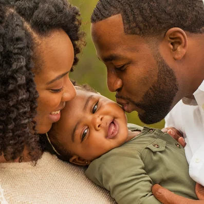 Glücklicher Mann und Frau mit lachendem Baby im Arm.