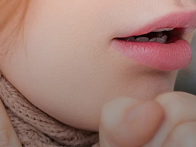 Junge Frau hustet in Faust.